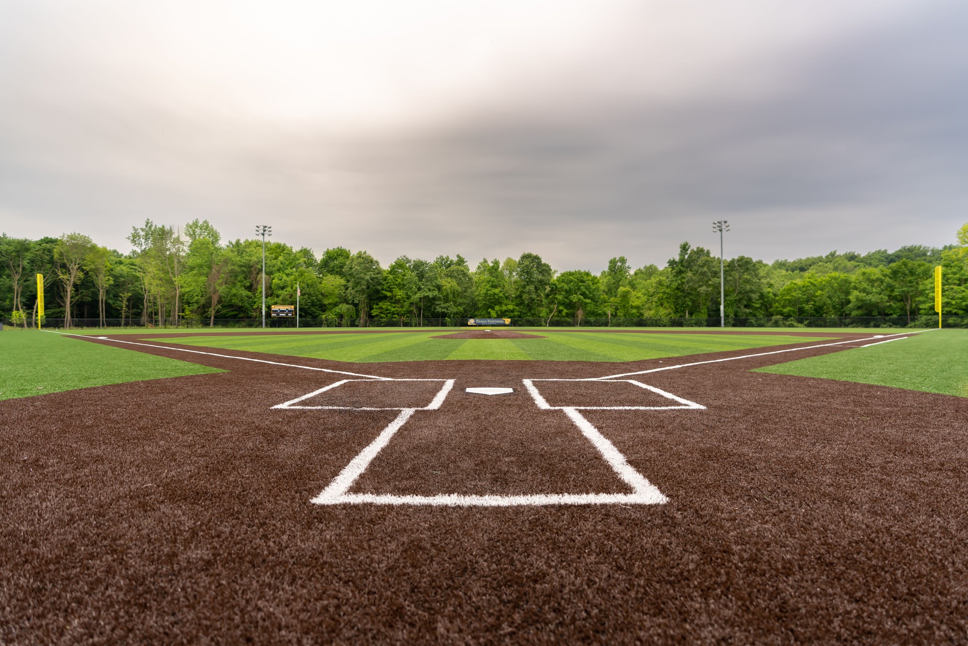 Scenic view of a baseball field with artificial grass in cloudy sky background